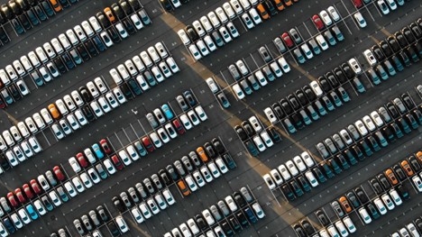 An overhead drone shot of a parking lot full of cars of all types and colors