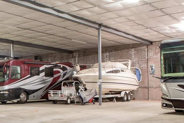 A boat is stored next to a red RV inside of Arizona Self Storage’s fully-enclosed massive storage barn in Sahuarita